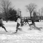 Students let off steam and kick up snow in a friendly game of snowshoe-football, 1939.