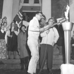 At the Statehouse in Augusta, announcer Bill Huckabee ’58 looks on as David Harper ’59 lights the torch signifying the start of the 1958 Winter Carnival.