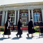 Now: (May) From left, Graham Veysey, John VanNostrand, and Eric Ursprung follow classmates to the dais during Commencement 2004, held on the Quad with Coram Library as a backdrop.  Photograph by Phyllis Graber Jensen.
