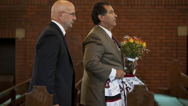 John Pappas, father of Troy '16, leaves the College Chapel at the end of the Oct. 11 memorial service, followed by head football coach Mark Harriman. Pappas holds Troy's jersey, signed by his teammates, and a floral arrangement from the service. Photograph by Phyllis Graber Jensen/Bates College.