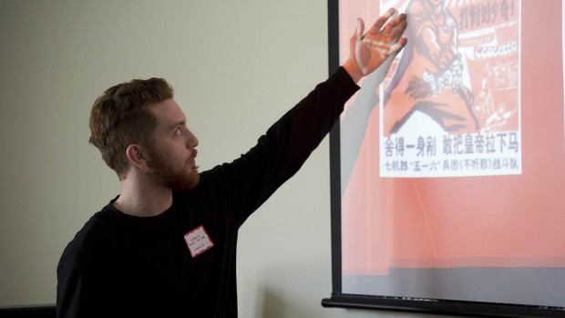 Clay Baldo '13 explains a Chinese political poster during the Mount David Summit. Photograph by Michael Bradley/Bates College College.