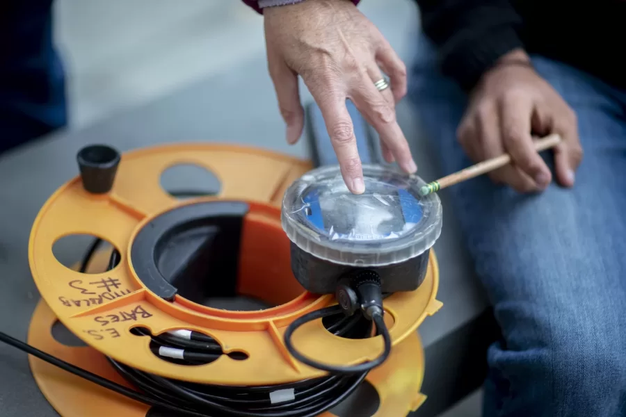 Professor of Earth and Climate Sciences Beverly Johnson teaches class at Lake Andrews with her students from EACS 240 - Environmental Geochemistry/Lab, where she asked the students to collect water and measure the following:
-- (dissolves) oxygen
-- specific conductivity
-- temperature
-- depth
Four students working behind Parker Hall gathered and measured their water with the sensor provided by Johnson to each small group:
Katie Caperton '23 in green pullover
Victoria Scott '23 in Bates sweatshirt
Henry King '22 in orange jacket
Peter Dunbar '23 in tan hat