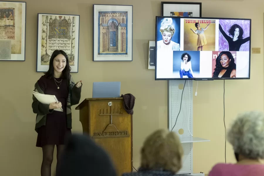 Frances White of ’23 New York City presents her religious studies senior thesis, “Women With Chutzpah.” to members of Temple Shalom Synagogue-Center in Auburn after a brunch on Sunday, Feb. 12, 2023.

“I just knew I wanted to work on something that was going to be funny and enjoyable and also kind of empowering and important to myself.”

— Frances White ’23 of New York City

Champagne and Coca-Cola sprayed in unison as a group of White’s friends gathered outside Ladd Library on Monday, Dec. 12, 2022, to watch White and her friend, Fenna Oliphant-Linden ’26 of Bethesda, Md., bind White’s thesis in religious studies, titled “Women with Chutzpah.”

“Women with Chutzpah” is about “the subversive means of Jewish humor for Jewish women specifically,” says White, who looked at five female Jewish comedians for her research: Sophie Tucker, Toby Fields, Gilda Radner, Ilana Glazer, and Tiffany Haddish.

“It was a way for me to just take what I love doing, which is making people laugh and using coping mechanisms of humor, and then seeing how that works in scholarly discourse.” White’s thesis adviser is Professor of Religious Studies Cynthia Baker.

White is also minoring in Africana, and her studies around the concept of race helped inform the focus of her thesis.

“A big part of my thesis was looking at how making fun of identity and humor is different if it's your identity, rather than someone else's.” It’s one thing when Jewish women themselves reclaim their pride in a Jewish body, White said, “but when other people are saying or using these stereotypes, it holds a very different impact.”

“How do we as Jewish women talk about ourselves and then use that as empowering, while also acknowledging we know what the anti-Semitic discourses are.”
