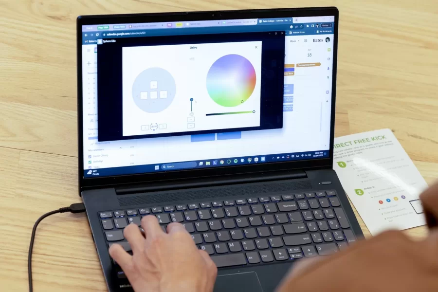 Small, but sophisticated.

That’s what first-year students of Professor of Mathematics Meredith Greer discovered about one kind of small robot during a visit to Bates by a team of Lewiston Public Schools educators on Nov. 14.

The team of instructional specialists and tech coaches brought Sphero BOLT robots with them during the morning visit to Chase Hall Lounge. Designed for educational and recreational purposes, they’re often used in schools to teach coding and robotics.

From left, first-year students Darien Chiang of Quincy, Mass., Julian Tilney of Arlington, Mass., and Finn Sheehy of Burlingame, Calif., get a handle on how to program the robots.

The students are in Greer’s First-Year Seminar, “Learning Math Using Crafts, Coding, and Games,” which investigates “how humans think about math at age 5, age 12, or age 18 and beyond.” During the semester, the students focused on learning through a variety of methods, including hands-on crafts, open-ended class meetings, and age-appropriate computer coding.

This was the educators’ third visit to the course, and for each visit, they brought with them age-appropriate robots.

Connecting with the Lewiston educators, and gaining insights into “specific activities they do with the robots at specific grade levels,” Greer explains, “has given us multiple chances to connect our studies with specific grade-level-based math learning standards that are used across the state of Maine.”

For the Lewiston educators, the three visits reflect growing outreach efforts into their community. “They were both enthusiastic and generous about bringing these lessons into our classroom,” says Greer. “Moving forward, we are continuing to think about ongoing collaborations.”