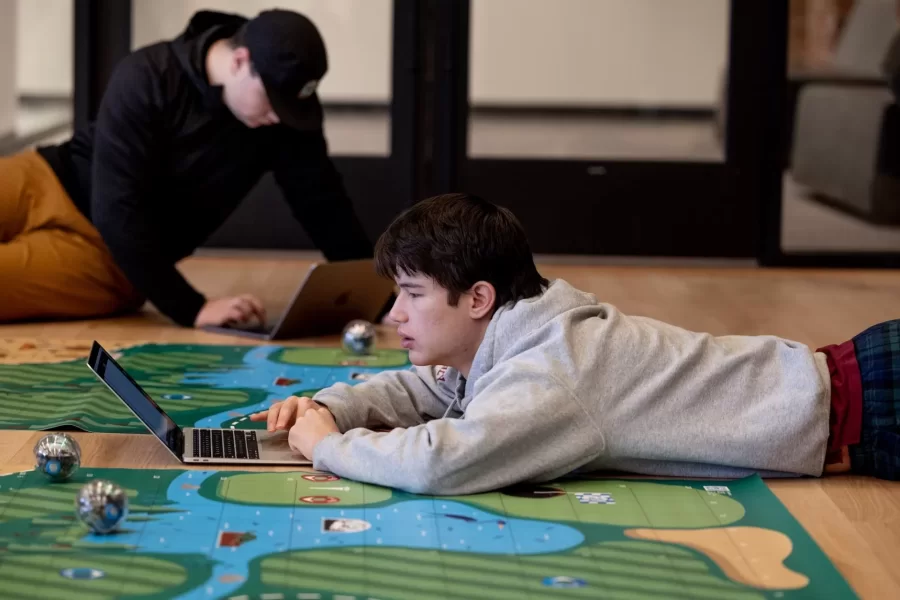 Small, but sophisticated.

That’s what first-year students of Professor of Mathematics Meredith Greer discovered about one kind of small robot during a visit to Bates by a team of Lewiston Public Schools educators on Nov. 14.

The team of instructional specialists and tech coaches brought Sphero BOLT robots with them during the morning visit to Chase Hall Lounge. Designed for educational and recreational purposes, they’re often used in schools to teach coding and robotics.

From left, first-year students Darien Chiang of Quincy, Mass., Julian Tilney of Arlington, Mass., and Finn Sheehy of Burlingame, Calif., get a handle on how to program the robots.

The students are in Greer’s First-Year Seminar, “Learning Math Using Crafts, Coding, and Games,” which investigates “how humans think about math at age 5, age 12, or age 18 and beyond.” During the semester, the students focused on learning through a variety of methods, including hands-on crafts, open-ended class meetings, and age-appropriate computer coding.

This was the educators’ third visit to the course, and for each visit, they brought with them age-appropriate robots.

Connecting with the Lewiston educators, and gaining insights into “specific activities they do with the robots at specific grade levels,” Greer explains, “has given us multiple chances to connect our studies with specific grade-level-based math learning standards that are used across the state of Maine.”

For the Lewiston educators, the three visits reflect growing outreach efforts into their community. “They were both enthusiastic and generous about bringing these lessons into our classroom,” says Greer. “Moving forward, we are continuing to think about ongoing collaborations.”