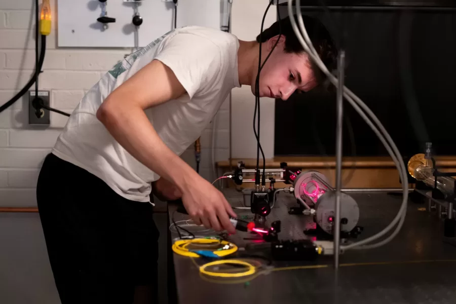 Assistant Professor of Physics Ryan Cole works with students in his Carnegie Science 156 lab on June 20, 2025. There is a secondary lab pictured in some of the photos that he and Paloma visited wearing goggles, where they used a laser to measure light frequencies. 

“Every once in a while, science makes sense,” he said at one point to the students.



“Paloma is building an instrument to study very precisely sunlight and specifically the spectrum of sunlight for applications ultimately in exoplanets (planets orbiting other stars)  detection and characterization.

And then this table, which is Carson, Quinn, and Audrey (and Andrew Liu who is not here today) They are measuring how atmospheric gases like methane — specifically green house gases — interact with light to ultimately help us measure those things better in the atmosphere.

Students photographed:

Audrey Schane ’25, physics major, who is working as a research assistant with Cole this summer,
Shown at the computer (striped t-shirt), where she is looking at a gas sample where she’s building something to control gas temperatures, with a vaccuum on the bottom. 

Paloma Rodriguez ’26, a physics major (black t-shirt)

Carson Moellering ’26, physics major, looking at how methane absorbs light in different conditions (light reflecting back and forth in mirrors (white t-shirt)

Qwynn Kobertz ’26, double major in physics and studio art, using a DSR laser exploring how to use this laser in a methane detecting app. (sunglasses on head) Here are two quick links that may help with some context for what we're doing in the lab.

My research website: https://sites.google.com/bates.edu/colelab/research-areas?authuser=0

NIST Article on optical frequency combs: https://www.nist.gov/topics/physics/optical-frequency-combs