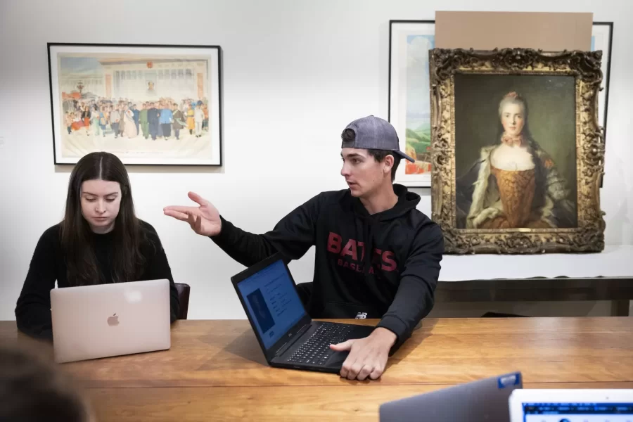 Historical Methods class, taught by Associate Professor of History Caroline Shaw, meets in the Lower Gallery of the Museum of Art in the Olin Arts Center. Working with Peter Philbin ’22, assistant museum curator, the students broke into several groups to consider four works of art, and how they would use that artwork along with other pieces in the museum collection, to create an exhibition.

HIST 399 - Historical Methods
This seminar refines students' proficiency as historians and prepares them to write their senior thesis. The course is designed around two interrelated goals. First, students analyze how different approaches to history and sources matter to understandings of the past. Second, students design and test their own arguments, drawing upon critical readings of primary sources and close engagement with historiography. The course culminates in the completion of individual thesis proposals. Prerequisite(s): one HIST 301 seminar.

Students at table, from head of the table, left:

Hanna Matthews ’24, brown sweater, long blonde hair
Matt Connelly ’24, white shirt
Chris Ly ’24, black hoodie
Emily Everett ’24, light gray sweater
Bridget Lee ’24, gray sweater, brown pants
Ben Fasciano ’23, gray sweater
James Guinee ’24,blue/green sweater
Ned Farrington ’24, blue flannel
Sebastien Kleitman ’24, black hat
Luke Linnehan ’24, black baseball hoodie and hat
Campbell McKendry ’24, black sweater, brown hat