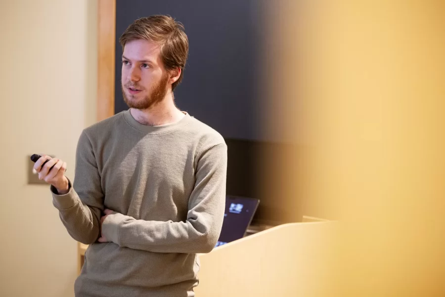 A student uses a device to click through slides while giving a presentation to their class.