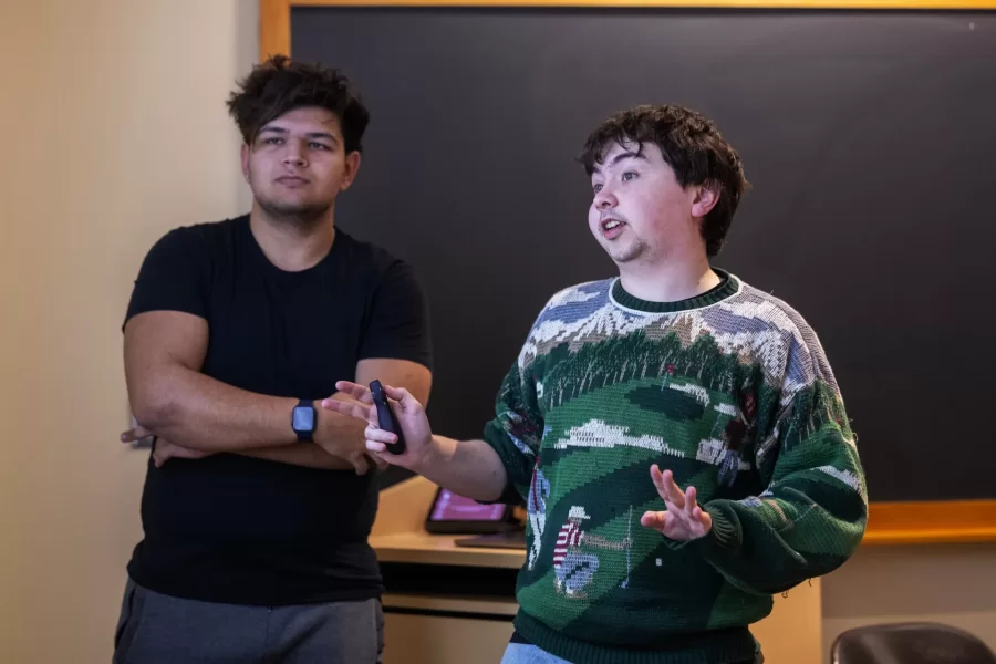 Two students glance at the projector screen while giving a presentation to their class.
