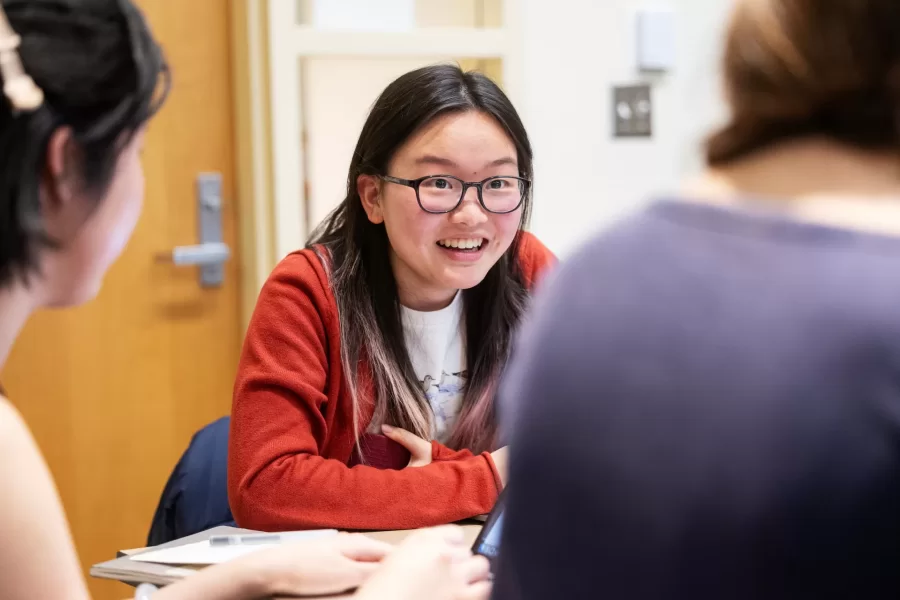 A student smiles and reacts to her peers during a class discussion.