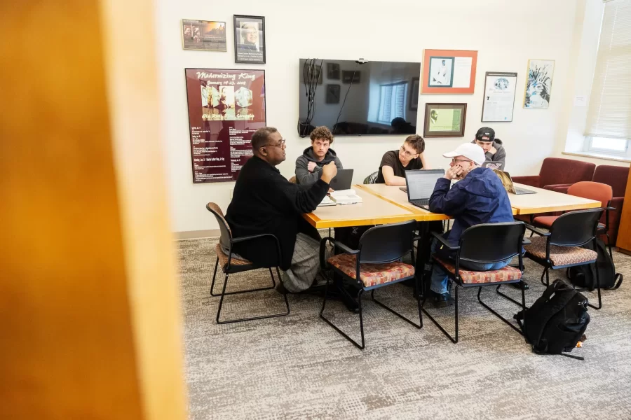 Four students and their professor engage in a small group discussion in a Pettengill Hall study lounge.
