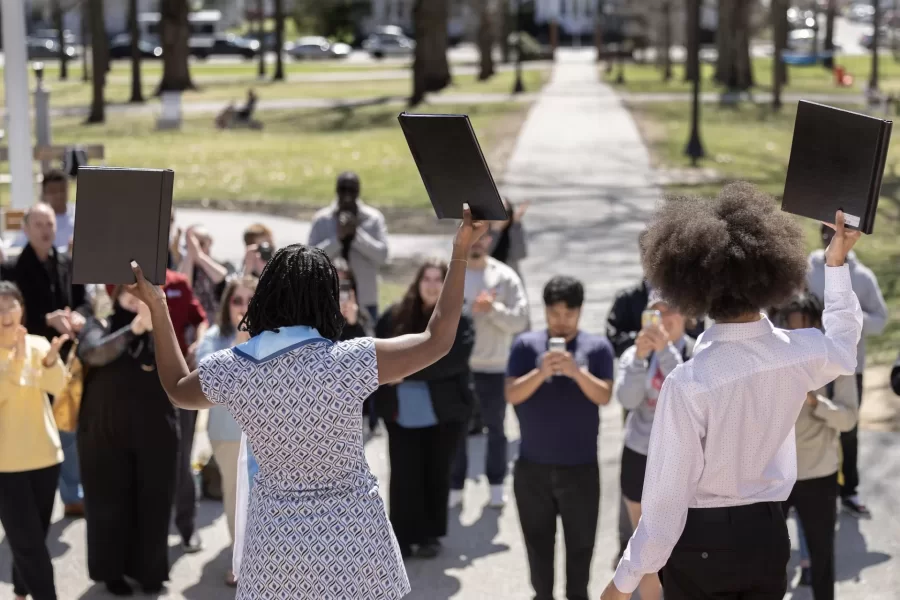 Two close friends who met on their first day at Bates chose to bind their senior theses together on the steps of Hathorn Hall on April 17, 2024.
In the company of friends, staff, and faculty, Aaliyah Moore ’24 and Prinnes Wilson’24 paid tribute to each other, to those gathered, and to family members who have supported them along the way.
Wilson, a psychology major from Las Vegas, wrote a thesis titled “The Relationship Between Aging and Proximity to Clothing,” under the supervision of Visiting Assistant Professor of Psychology Katherine Mathis. After the binding, Wilson expressed pride in his thesis. “It’s a good representation of me,” he said.
Moore, a double major in Africana and politics from Phoenix, Ariz., bound two theses. Her honors thesis in Africana, written under the supervision of Professor of English Therí Pickens, is titled: “Alice Walker’s ‘The Color Purple’: An Authentic Depiction of Confinement in Historical Fiction.” Moore called Pickens her “spiritual guide” whose “unwavering support, grace, and kindness know no bounds.”
Moore’s politics thesis, written under the supervision of Professor of Politics Stephen Engel, is titled “Rethinking the Supreme Court’s Approach to Discrimination Cases: Adopting a Comprehensive Framework.”