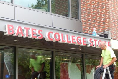 A technician for Exposé Signs & Graphics has just finished mounting a sign for the College Store on a front canopy at 65 Campus Ave. (Doug Hubley/Bates College)