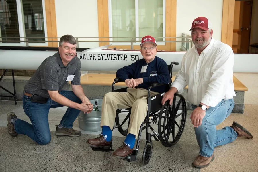 Mechanical Services Manager Alan Kelly, left, Ralph Sylvester ’50 and Bates Rowing Head Coach Peter Steenstra pose for a portrait in front of the new Bates rowing shell at Perry Atrium in Pettengill Hall on April 29, 2023. Coach Steenstra presented Sylvester with a blade during the dedication ceremony making Sylvester the only non-rower to receive one.
