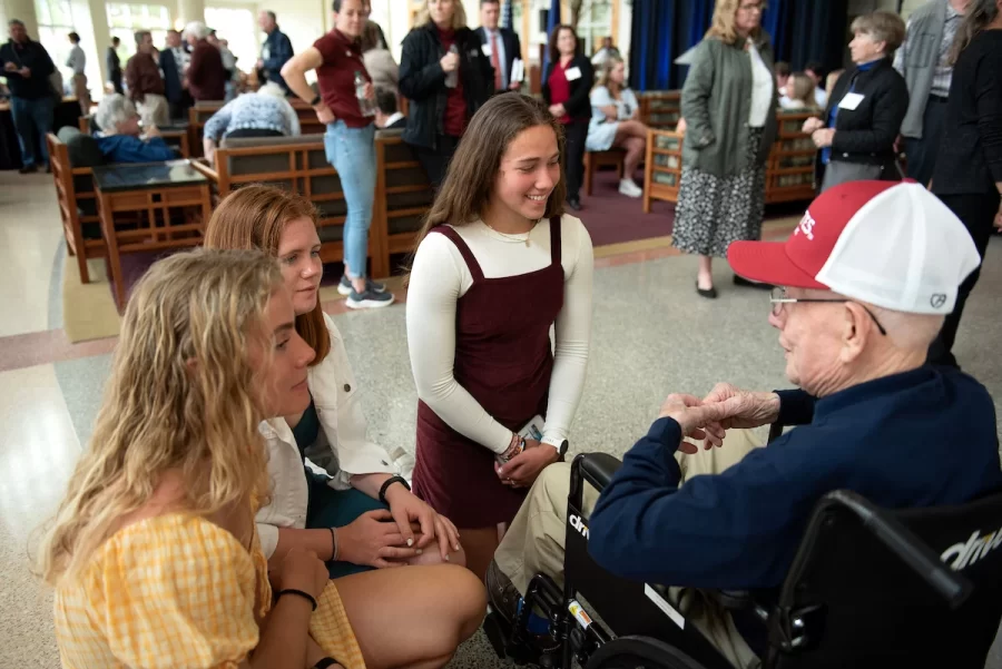 Members of the Bates rowing team from left: Molly Connors ’23 of Westwood, Mass.; Katarina Dickson ’24 of Princeton, Mass. and Eliana Weissmann ’24 of Newton, Mass. talk with Ralph Sylvester ’50 during the dedication of the new rowing shell at Perry Atrium in Pettengill Hall on April 29, 2023.