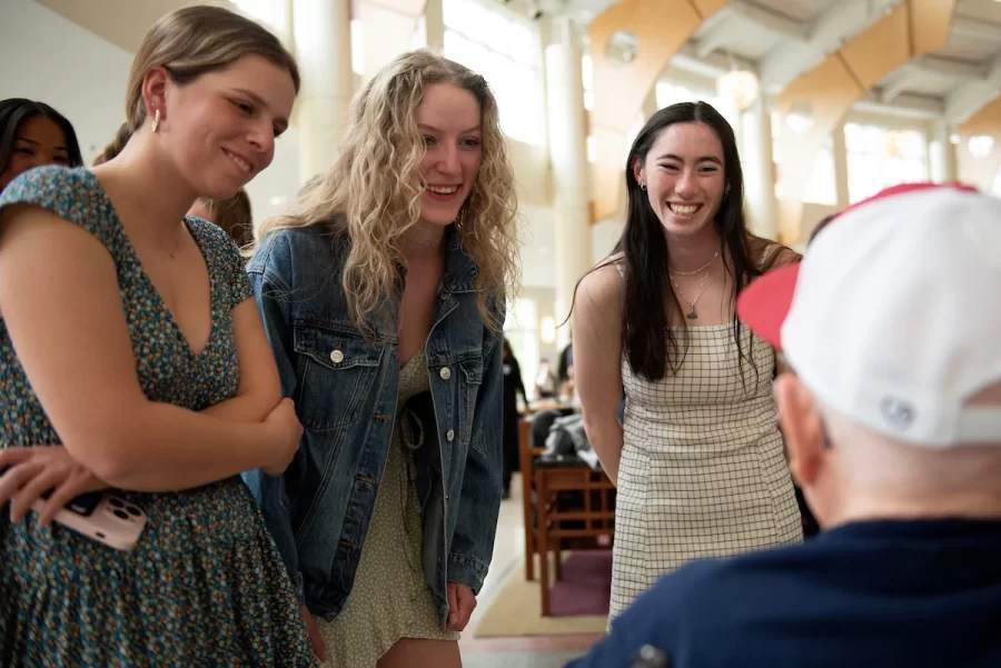 Members of the Bates rowing team Lucy Del Col ’24 of Wellesley, Mass.; Oli Seline ’24 of Delaware, Ohio and Hannah Braslau ’23 of Chelmsford, Mass. talk with Ralph Sylvester ’50 during the dedication of the new rowing shell at Perry Atrium in Pettengill Hall on April 29, 2023.