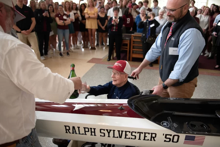 Ralph Sylvester ’50 christens the new rowing shell at Perry Atrium in Pettengill Hall on April 29, 2023. Bates Rowing Head Coach Peter Steenstra presented Sylvester with a blade during the dedication ceremony making Sylvester the only non-rower to receive one.