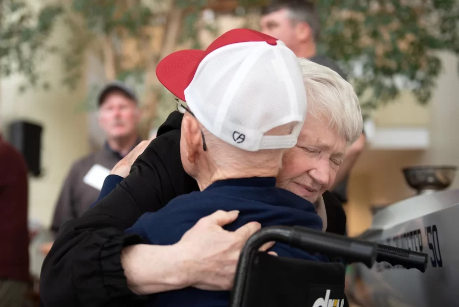 Cindy Peters of Lewiston hugs friend Ralph Sylvester ’50 during the dedication of the new rowing shell at Perry Atrium in Pettengill Hall on April 29, 2023.