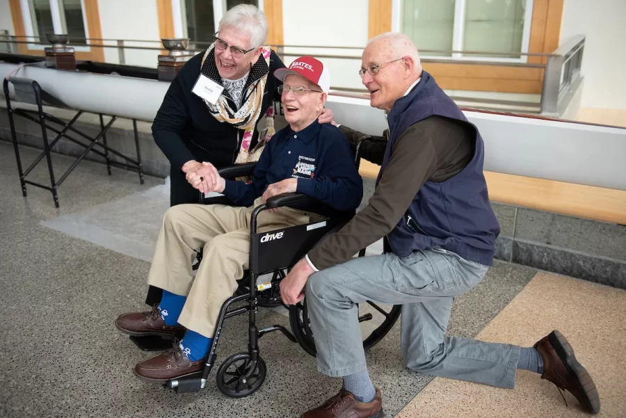Dodie, left, and John Wait of Waterford congratulate friend Ralph Sylvester ’50, center, during the dedication of the new rowing shell at Perry Atrium in Pettengill Hall on April 29, 2023.