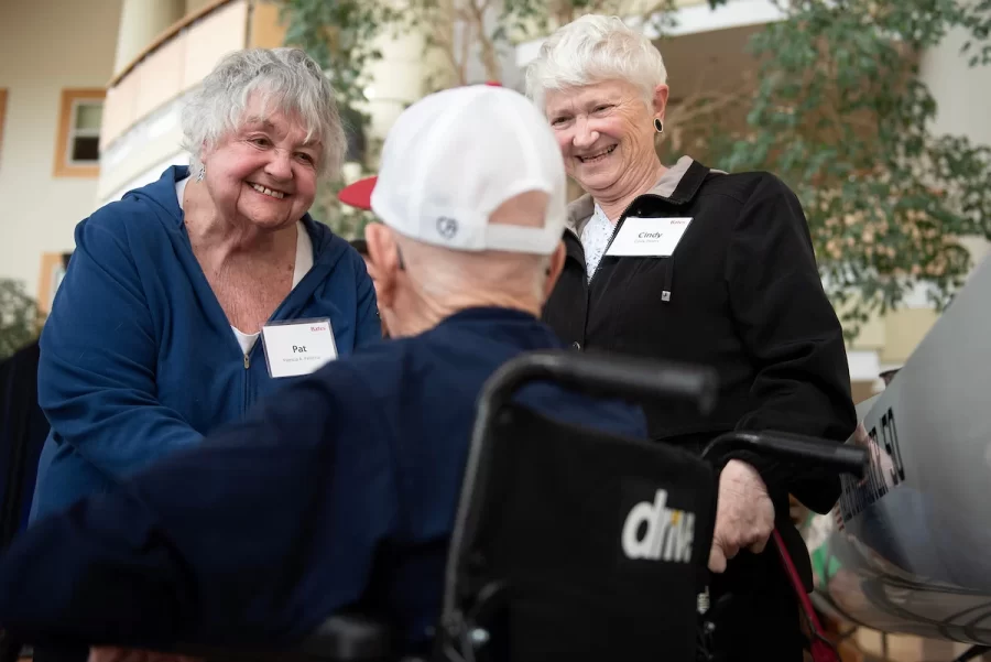 Pat McCluskey of Peru, left, and Cindy Peters of Lewiston congratulate friend Ralph Sylvester ’50 during the dedication of the new rowing shell at Perry Atrium in Pettengill Hall on April 29, 2023. McCluskey and Peters were teachers at Edward Little High School where Sylvester’s late wife worked.