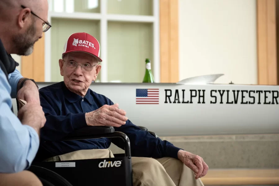 Vice President for Finance and Administration and Treasurer, left, talks with Ralph Sylvester ’50 during the dedication of the new rowing shell at Perry Atrium in Pettengill Hall on April 29, 2023. Bates Rowing Head Coach Peter Steenstra presented Sylvester with a blade during the dedication ceremony, making Sylvester the only non-rower to receive one.