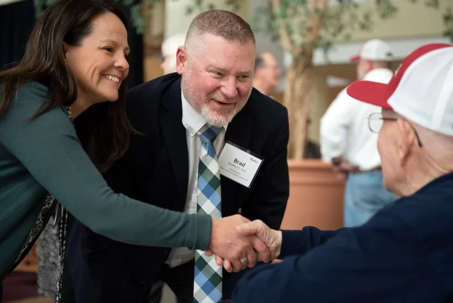 Maine Veterans Home Administrator Bradford Peck, center, and his wife, Angela Peck, left, congratulate Ralph Sylvester ’50 during the dedication of the new rowing shell at Perry Atrium in Pettengill Hall on April 29, 2023. Bates Rowing Head Coach Peter Steenstra presented Sylvester with a blade during the dedication ceremony, making Sylvester the only non-rower to receive one.