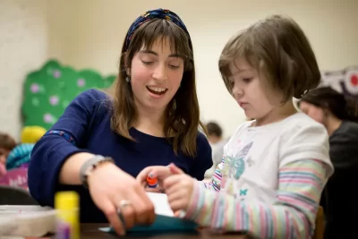Alisa Amador ’18 of Cambridge, Mass., works with a budding author on designing a chapter book at the Lewiston Public Library. Amador volunteers with the mobile Art Van for area children. (Phyllis Graber Jensen/Bates College)