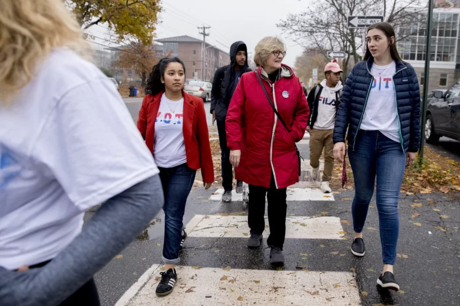 President Clayton Spencer escorts a group of Bates students to the polls on election day, Tuesday, Nov. 6.
.
In an effort spearheaded by Bates Democrats, Bates Republicans, and the Harward Center for Community Partnerships, Bates students led a bipartisan effort to get out the vote. Volunteers led walking groups from Commons on the hour and every 15 minutes during peak times to the Lewiston Armory on Central Avenue.

Student IDs:

In red jacket, Maya Seshan
In blue jacket with blue jeans, Elektra Smicka
In maroon pants, Elise Grossfeld
On scooter, Michael Ratzimbazfy
Student in blue hood, Harkirat Lally 
In glasses, long blondish hair, tied VOTE shirt and bean boots, Maya Chessen



His name is Michael Ratzimbazfy. The girl in the blue jacket 's name is Elektra Smicka, the student standing on the far right in maroon pants is Elise Grossfeld, the student in the bean boots is Maya Chessen, and the student behind her with dark brown hair is Ella Westerfield.