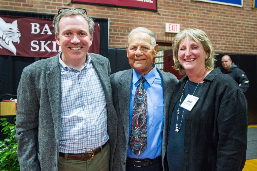 A huge crowd of Bates skiing faithful turned out in Alumni Gymnasium during Back to Bates Weekend to recognize legendary Bates skiing, baseball, and golf coach Bob Flynn P’85, P’89 with the naming of the newly renovated Alpine and Nordic ski rooms, made possible by generous gifts in honor of Coach Flynn. Surrounded by friends and family — including his wife, Benita, daughters Becky Flynn Woods ’89 (current Nordic ski coach); Elizabeth A. Flynn P’14, P’17, P’17; and Susan Flynn Dorris ’85 — Flynn received a rousing chorus of “We love you coach, Oh yes we do!” after being lauded by Director of Athletics Kevin McHugh, President Clayton Spencer, and Bates Trustee Steve Fuller ’82, P’13. Pictured here (l–r) are Bates Trustee Steve Fuller ’82, P’13; Coach Flynn, and Debbie Fuller ’82, P’13.