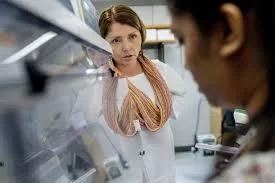 a professor stands in a lab speaking to a student