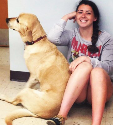A yellow lab and a girl sitting on the floor being goofy