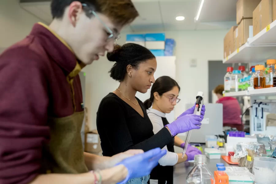 Three students work with lab equipment in a Bonney Science Center lab.