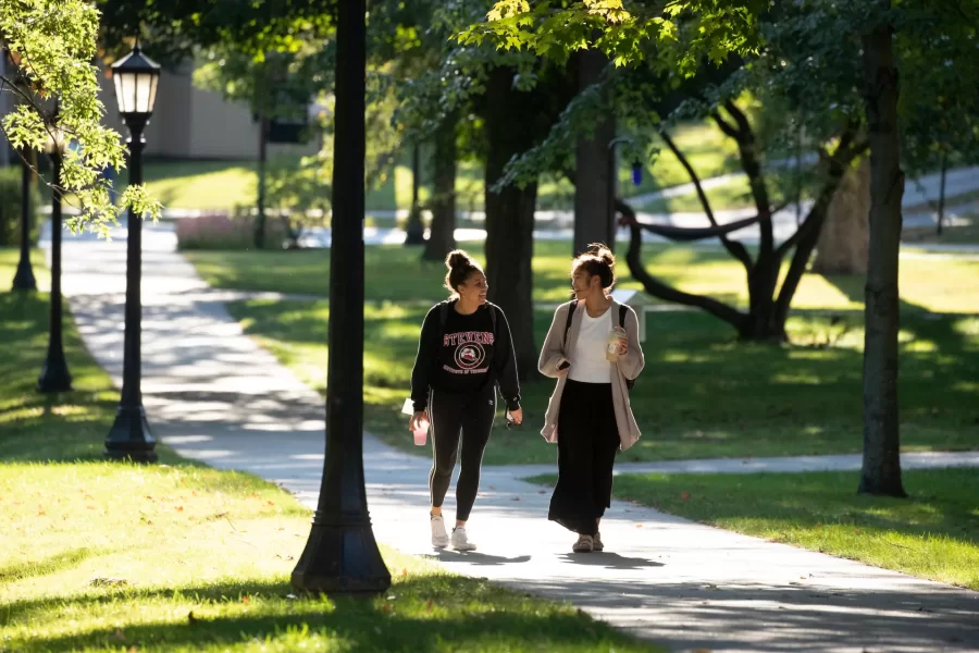 Two students walk down a path on the historic Quad on a sunny afternoon.