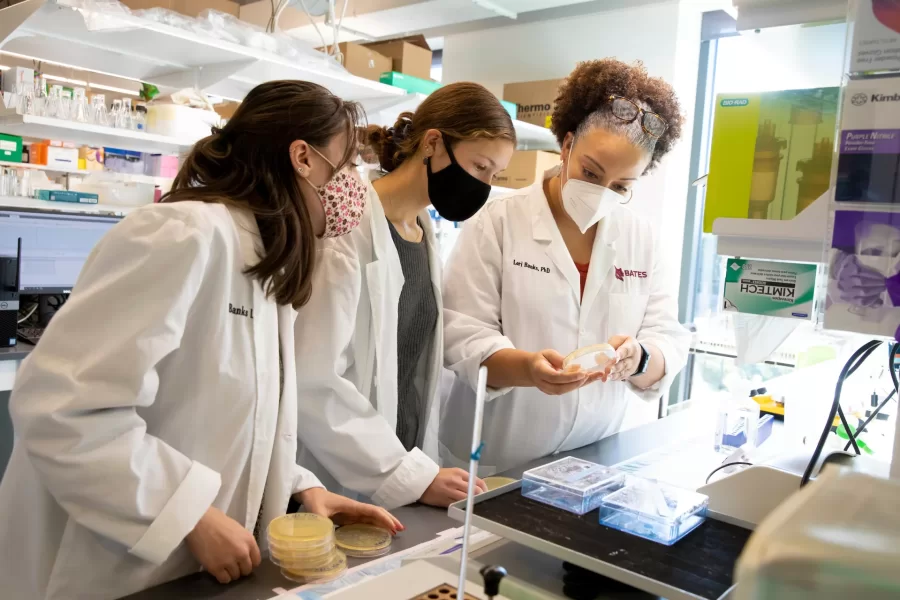 Two students and a professor look at a sample in a petri dish in a Bonney Science Center lab.