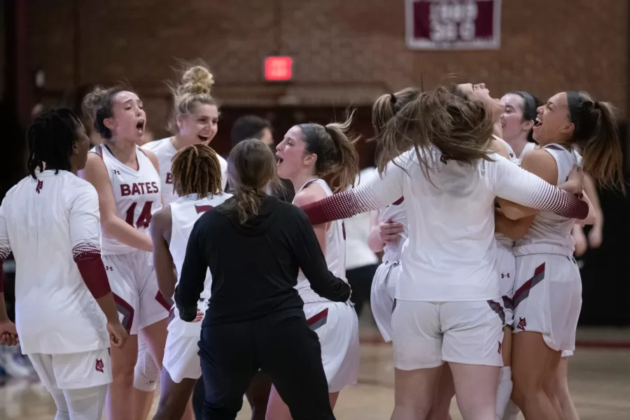 The Bates women's basketball team jumps in a huddle in celebration of their championship win over Amherst.