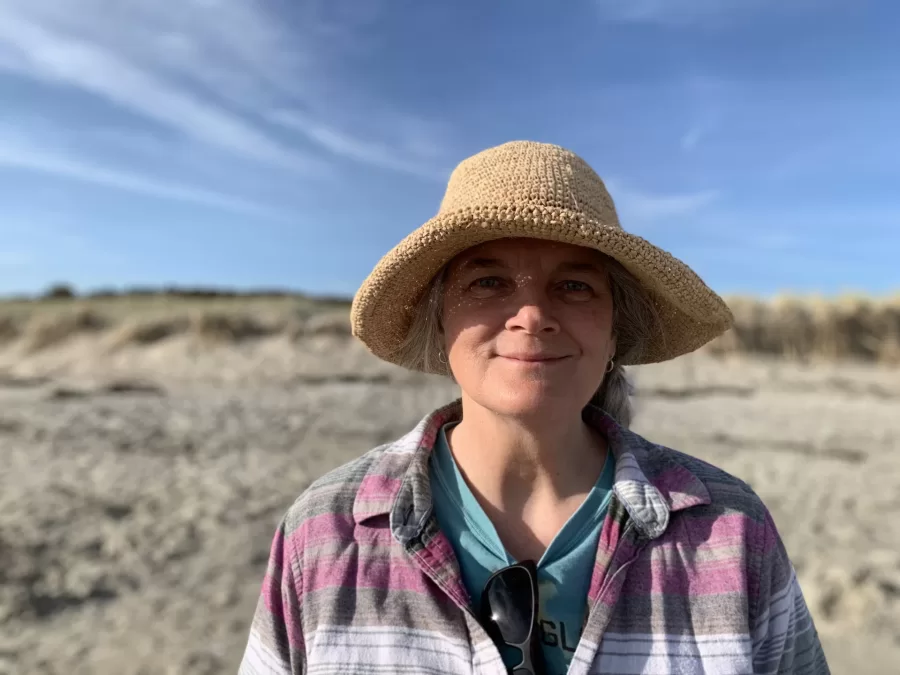 Photo of Professor Bev Johnson against blurred background of sand and sky