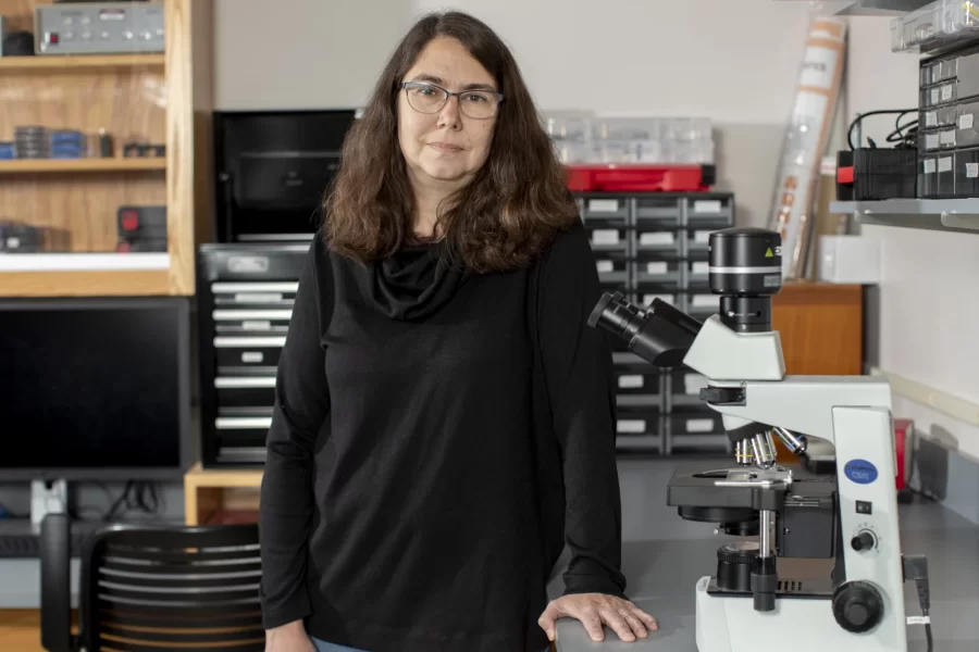 Paula Schlax stands next to a bench with a microscope in her laboratory.