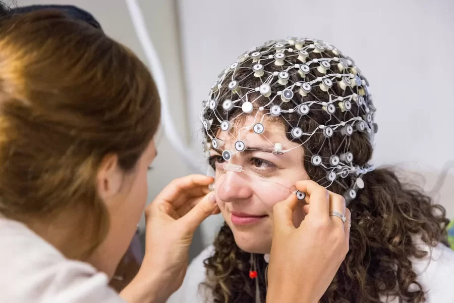To practice her skills, a colleague fits Melody Altschuler '17 of Lyme, Conn., with an electroencephalography net, a non-invasive way to measure brain activity. Altschuler was a summer intern at Boston Children's Hospital under Harvard Medical School's Susan Faja, a leader in autism research. (Josh Kuckens/Bates College)
