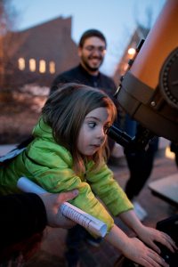 All kids agree; the moon looks WAY better up close! . Isla Shea, 6, of East Auburn School, uses a Carnegie telescope with 2,000x eye strength to view the moon as Evan Goldberg '19 looks on during last night's Bates Astronomy Extravaganza co-hosted by the Harward Center for Community Partnerships and the Bates College Physics and Astronomy Department. . Students in Astronomy 106, taught by Assistant Professor of Phyiscs Aleks Diamond-Stanic, ran hands on activities and planetarium shows to introduce children to black holes, galaxies, moons, planets, and more. Bates provided a fun night of getting kids excited about science.