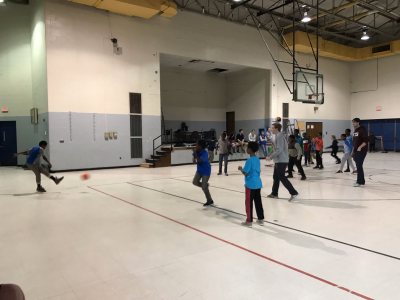 Bates Men’s Soccer players at Longley Elementary School helping coach a soccer game with the students at recess. 