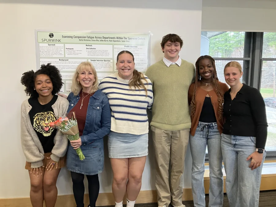 Research students and their partner pose in front of their research poster.