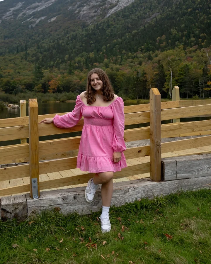 a student poses with a wooden fence in the background