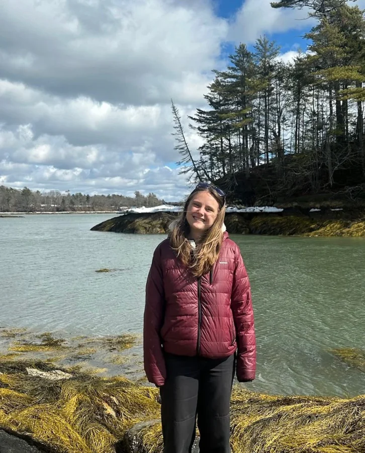 a student poses on a rocky shoreline