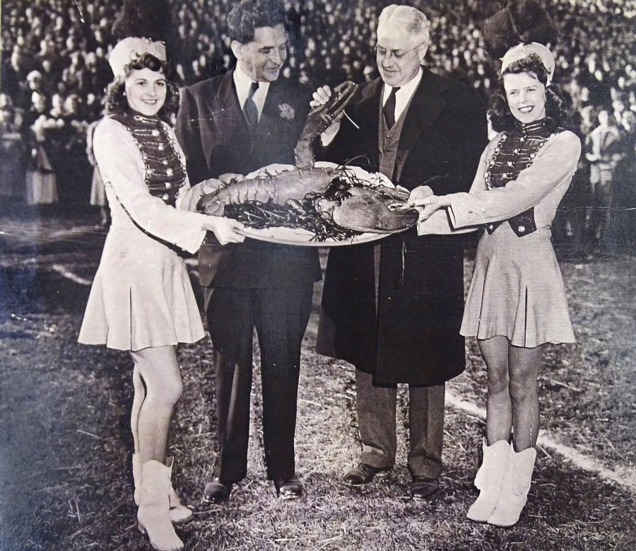 At halftime of the 1946 Glass Bowl between Bates and the University of Toledo, Ohio Gov. Frank Lausche (second from right) checks out the business end of an 18-pound lobster given by Bates athletic director Monte Moore '15 (second from left) on behalf of Maine Gov. Horace Hildreth. (Muskie Archives and Special Collections Library)