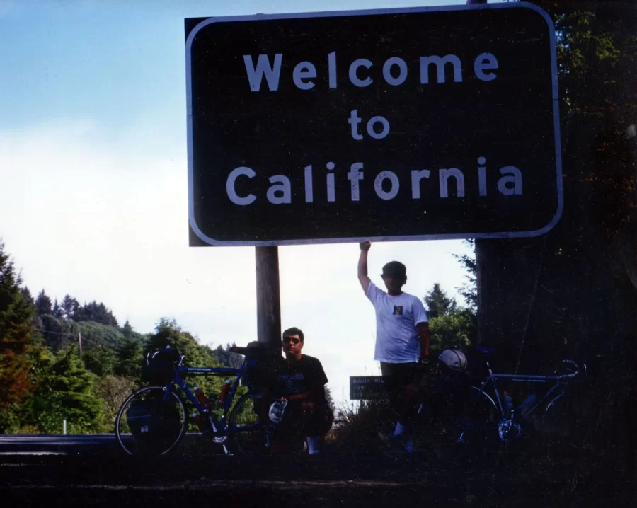 Tom Germano and Bill Scott pause by a road sign duering a long-distance bicycle trip