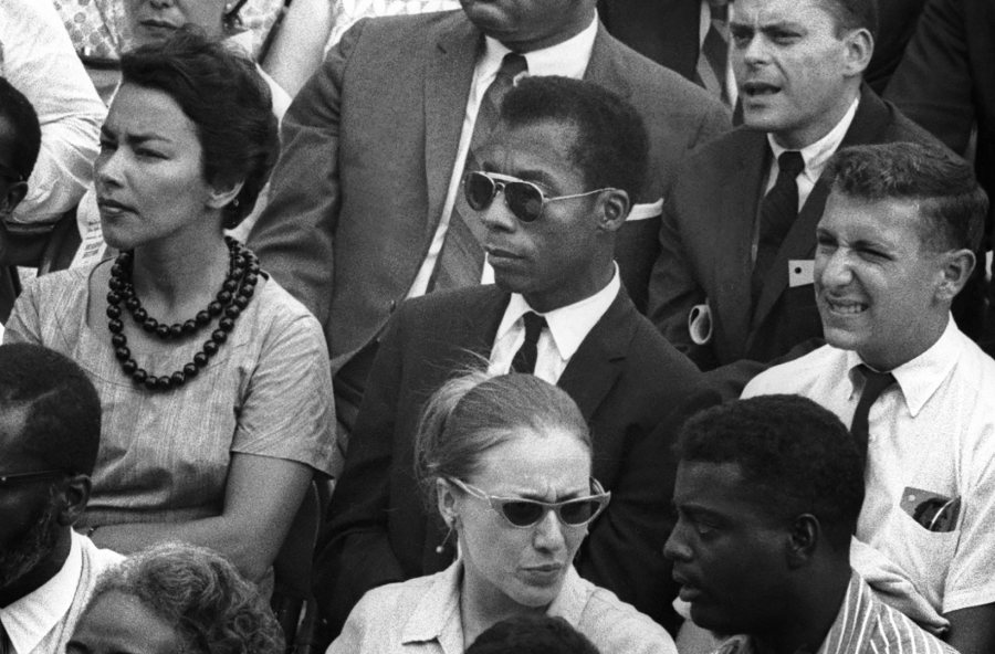 Author James Baldwin, at center, is shown in a still image from the film <em srcset=