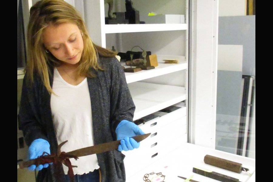 Shelbie McCormack examines a Vietnamese ceremonial dagger while cataloging objects for Bates College Museum of Art