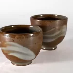Name: Jack FruechteTitle of Work: Tea BowlsYear: 2022Medium: Stoneware w/ porcelain slip and shino glazeSize: 3.5”x3.5” each