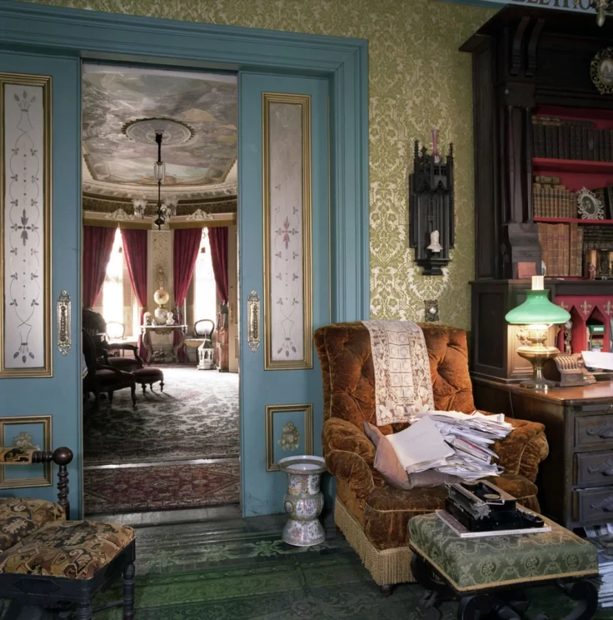 Art photograph of an ornately decorated house's interior, shot from the library, looking into a sitting room