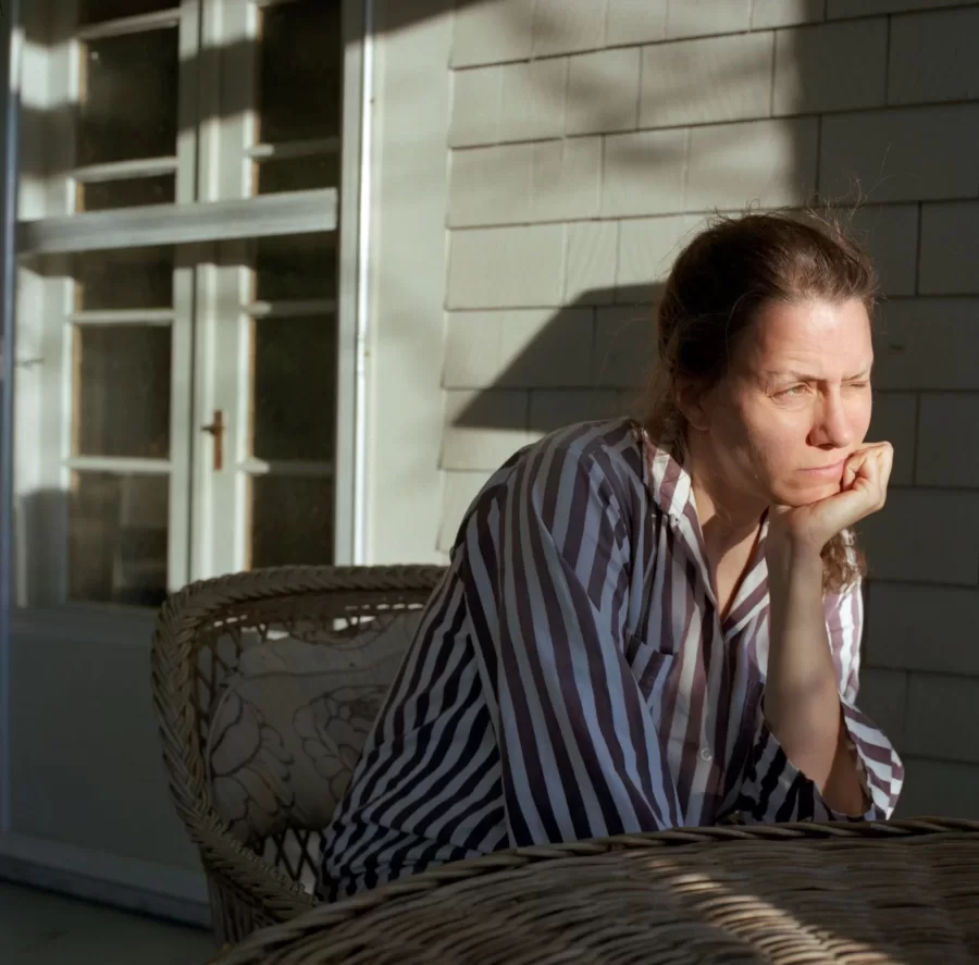 A woman in a red and white striped shirt sits mostly in shadow, her eyes mostly closed against bright light across her face